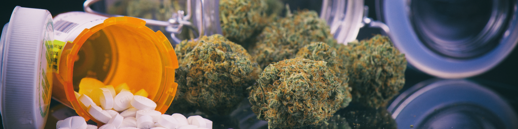Cannabis buds sitting next to a spilled pill bottle.