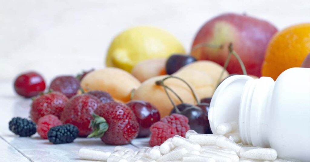 Close up view of different types of berries and a spilled bottle of pills