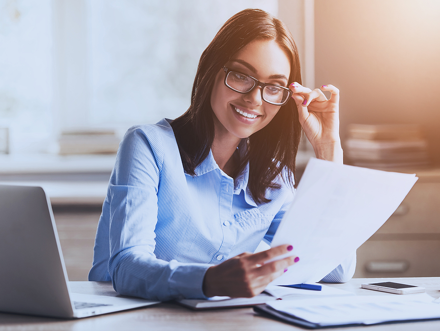 Businesswoman holding her glasses and looking at paperwork