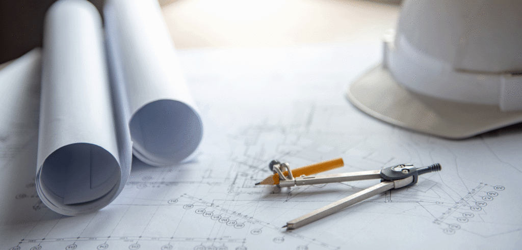 Closeup view of hard hat, architect plans, pencil and protractor