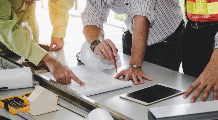 Businessmen looking over a drafting table with design plans