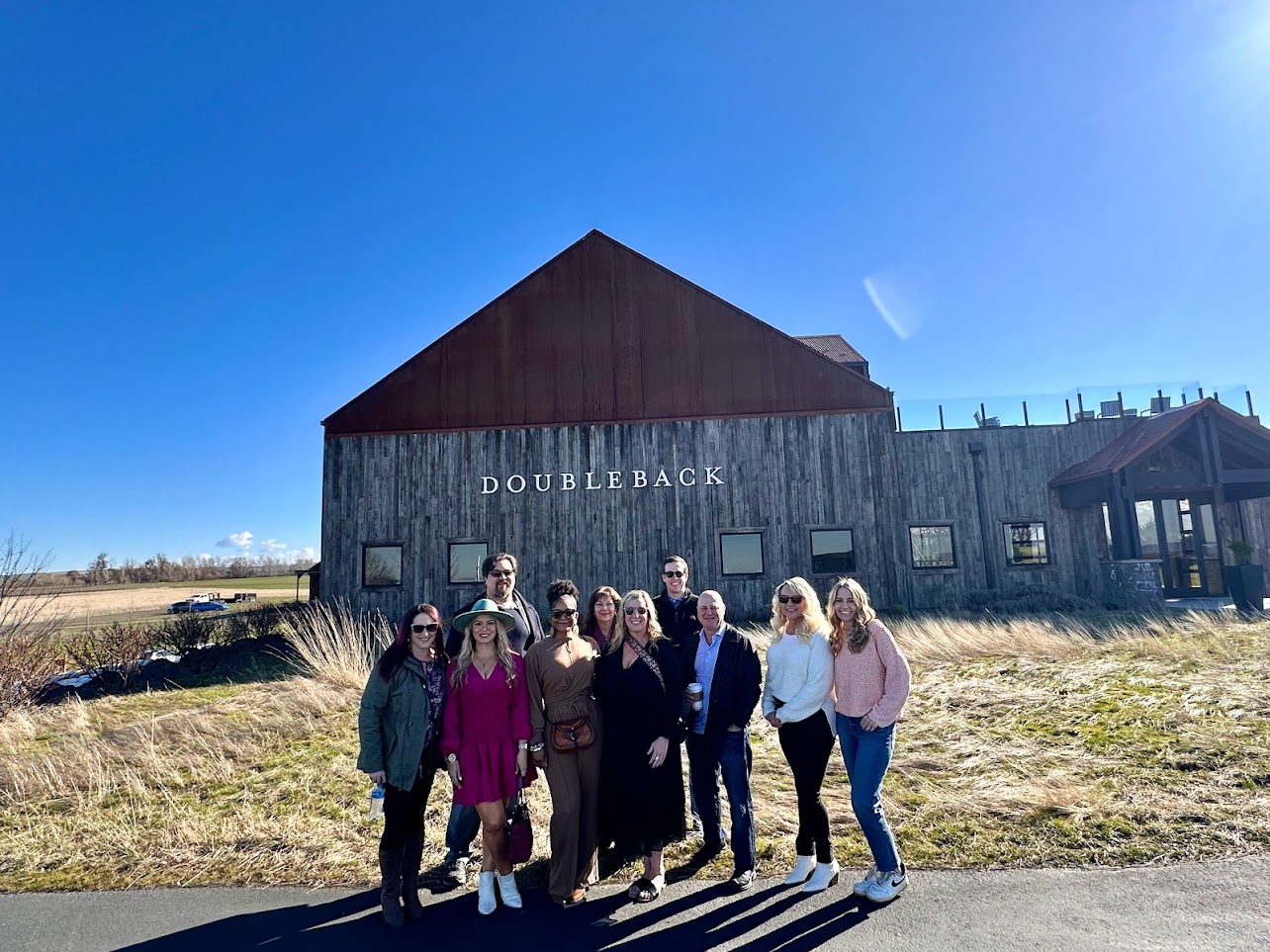 Underwriting team posing in front of a barn at Doubleback