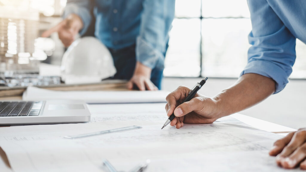 Hands of architect or engineer working on blueprint for project with partner