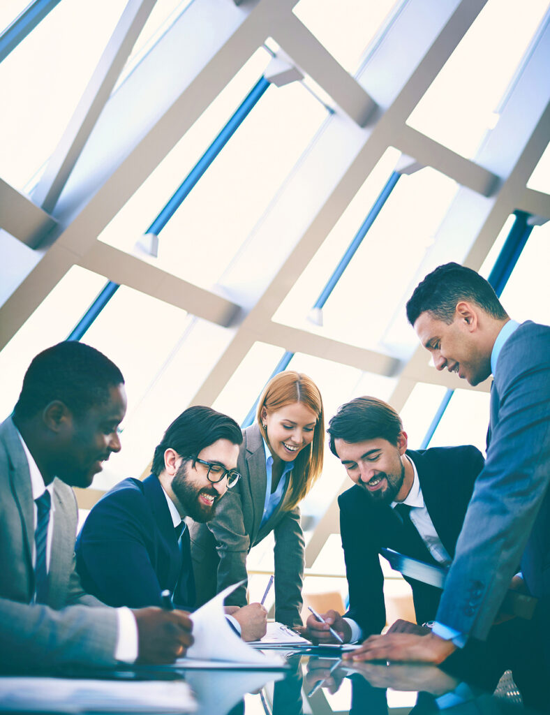 Group of businesspeople hovering over a table looking at paperwork 