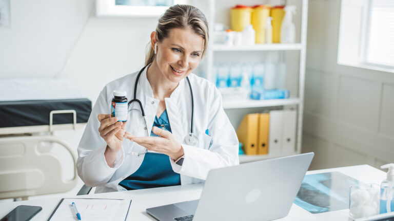 Dr. on a virtual care visit showing a pill bottle to the computer screen
