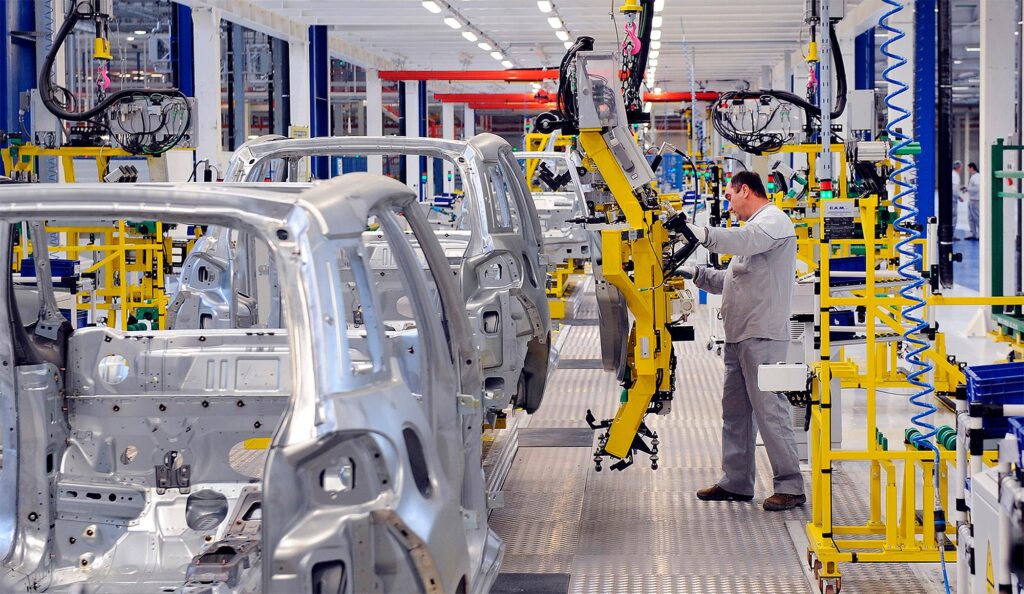 Man using robotics to work on a car assembly line