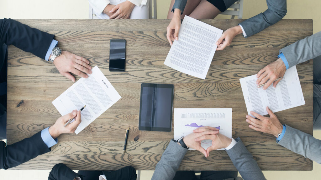 Overhead view of 4 businesspeople discussing contract risk management