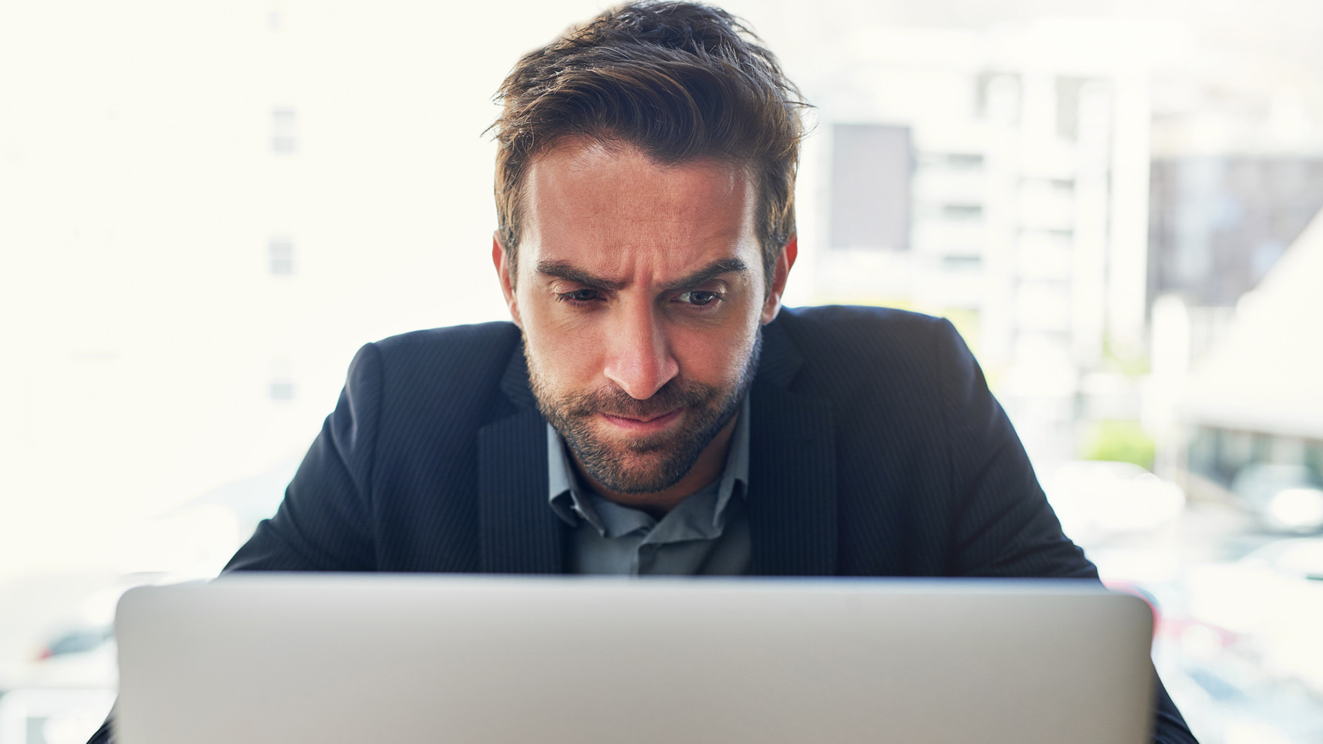 Closeup of businessman looking at a laptop screen with a confused look