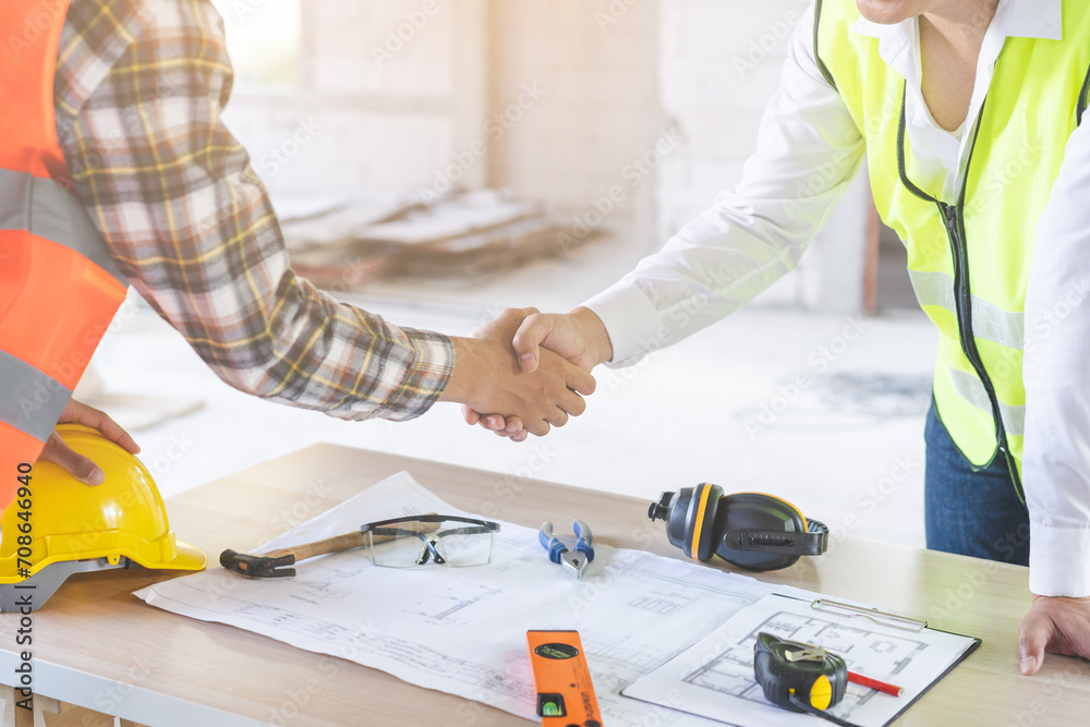 Two architects looking over drawing plans and shaking hands